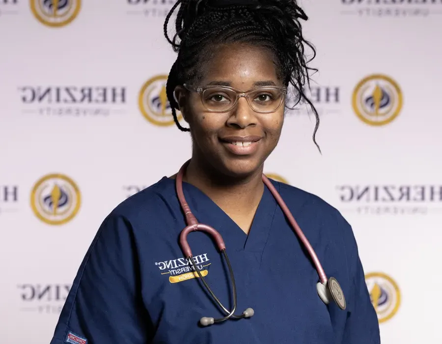 Herzing nursing student in blue scrubs wearing stethoscope smiling for portrait photo